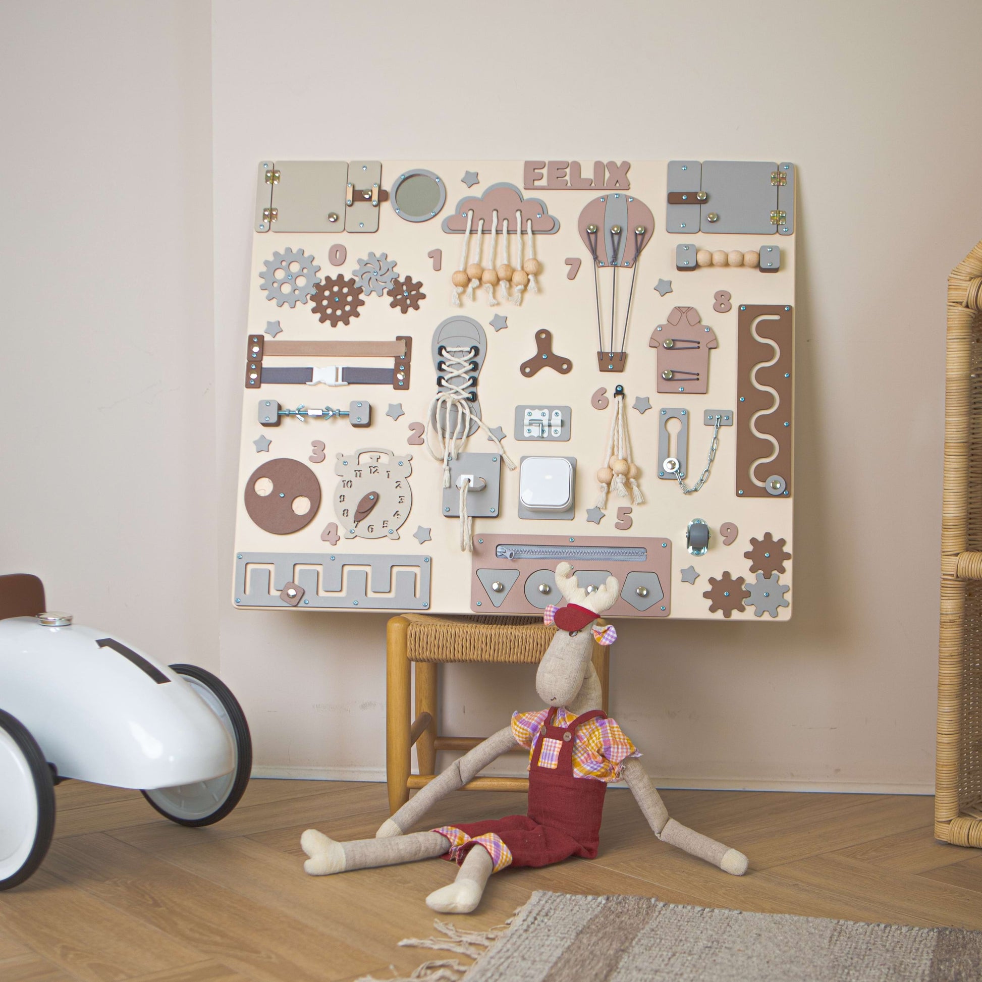 Kinderzimmer mit holz motorikwand mit mechanischen Motiven und einem Plüschtier auf dem Boden.
