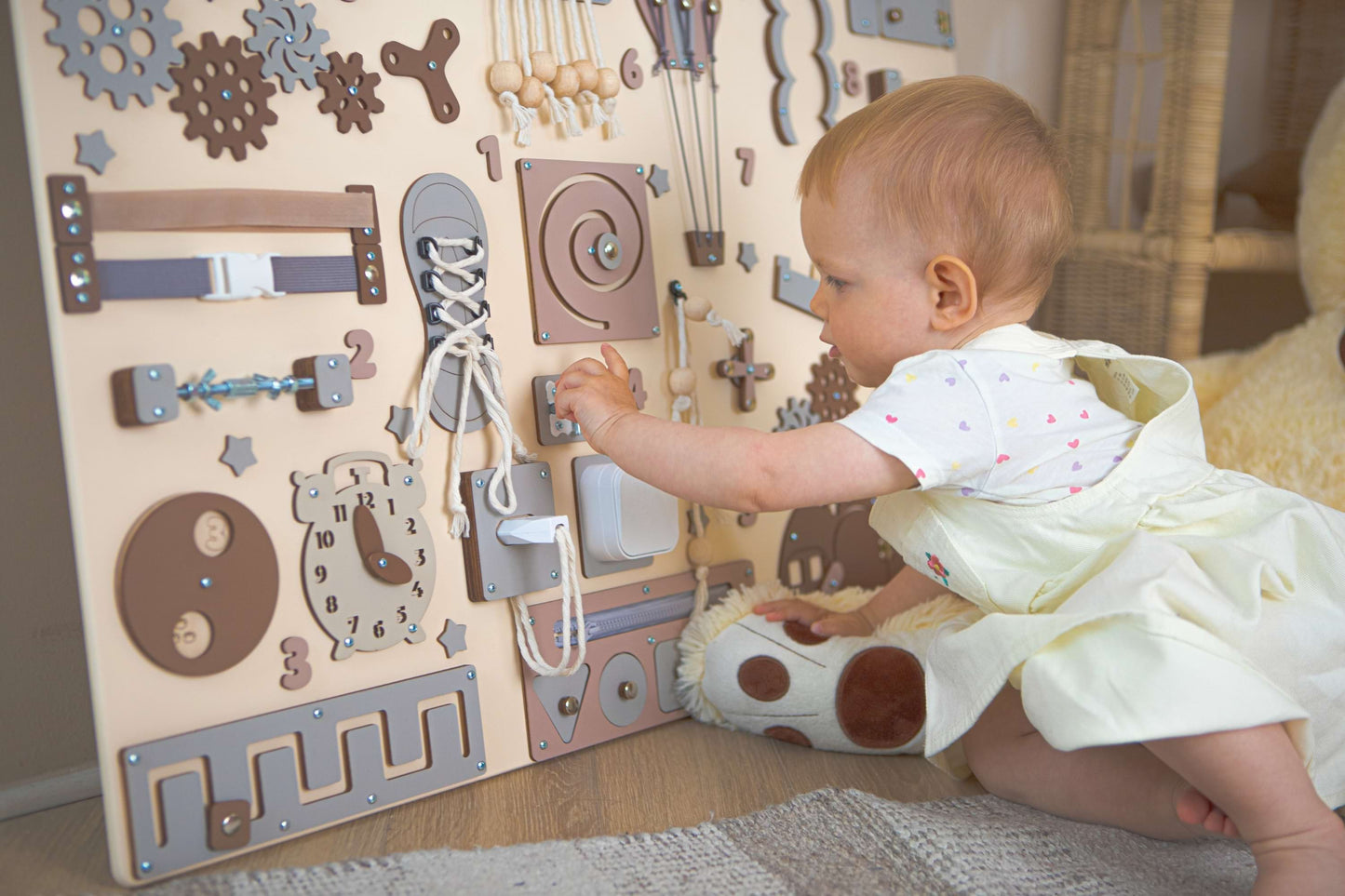 Baby spielt mit einem motorikbrett mit verschiedenen Formen und Strukturen.