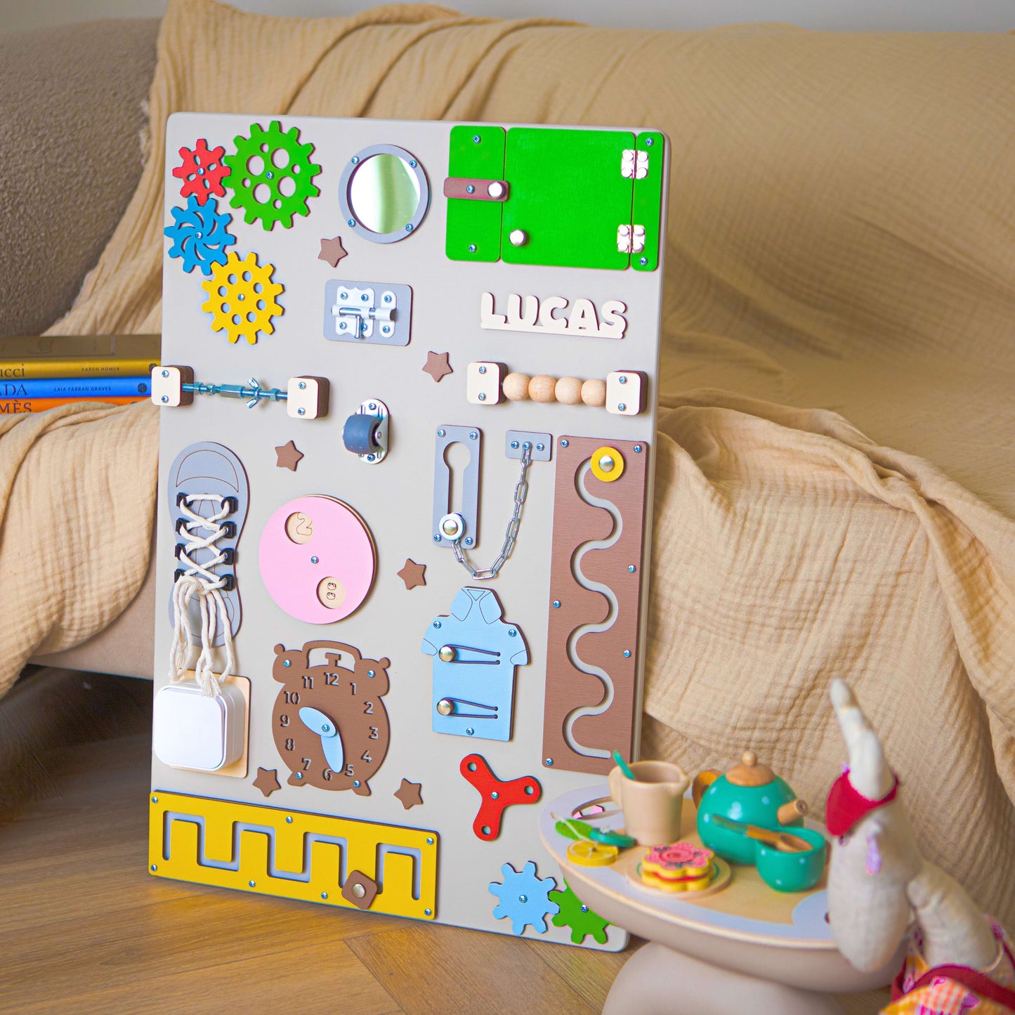 Buntes Aktivitätsbrett für Kleinkinder mit verschiedenen pädagogischen Elementen auf einer Holzoberfläche.