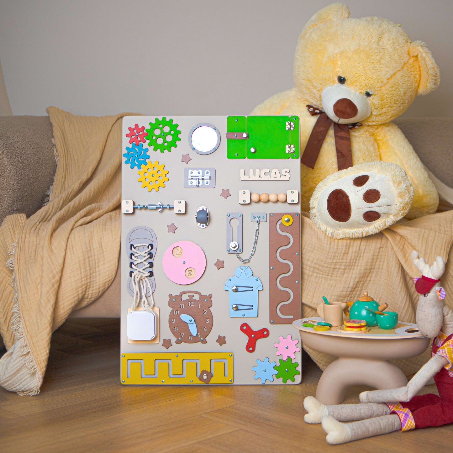 Tableau d'activités pour enfants avec engrenages, serrures et autres éléments mécaniques sur fond beige.
