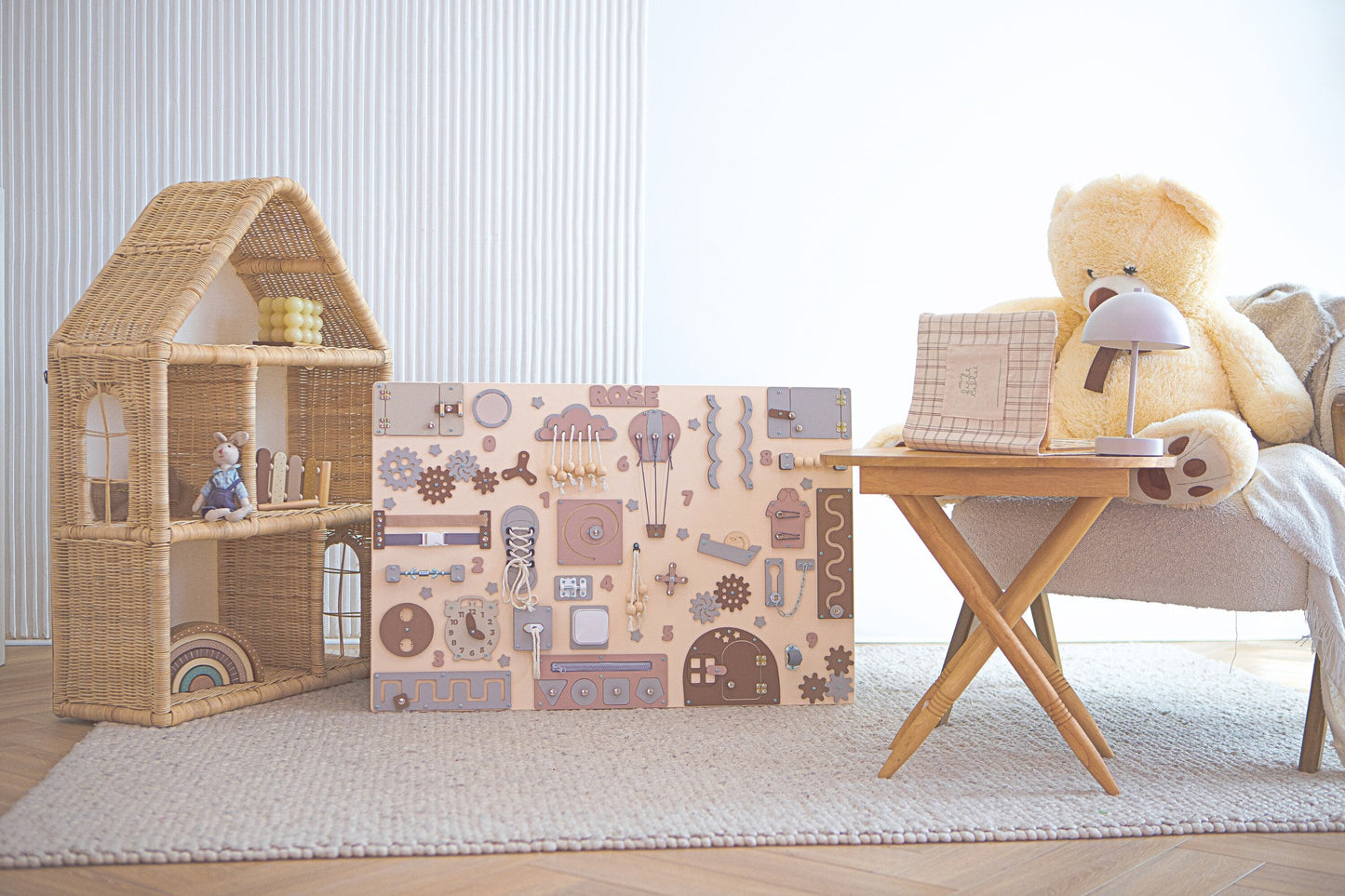 Kinderspielbereich mit einem Puppenhaus aus Korbgeflecht, einer Aktivitätstafel und einem Teddybär.