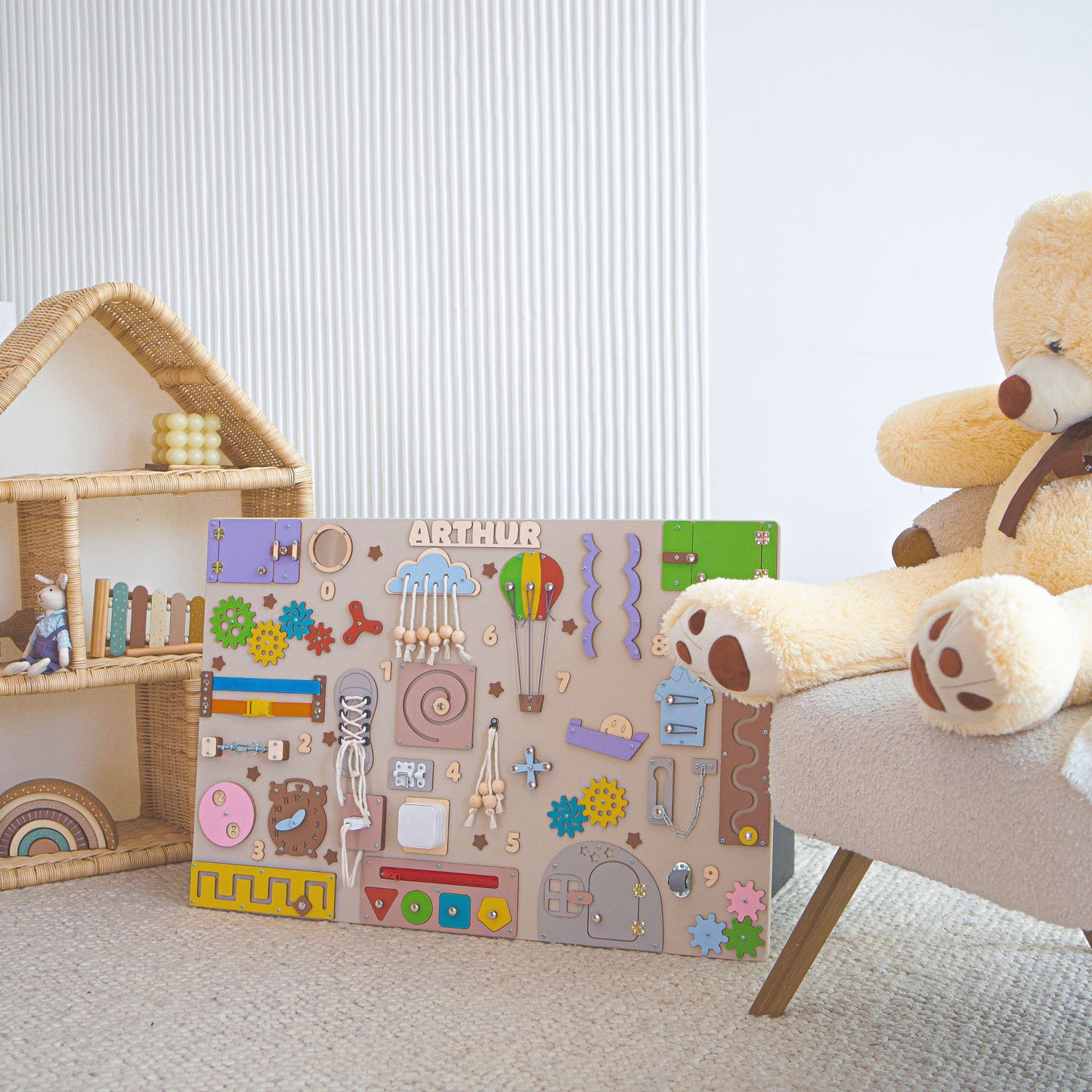 Kinderspielbereich mit Holz busy board, Teddybär und Puppenhaus.