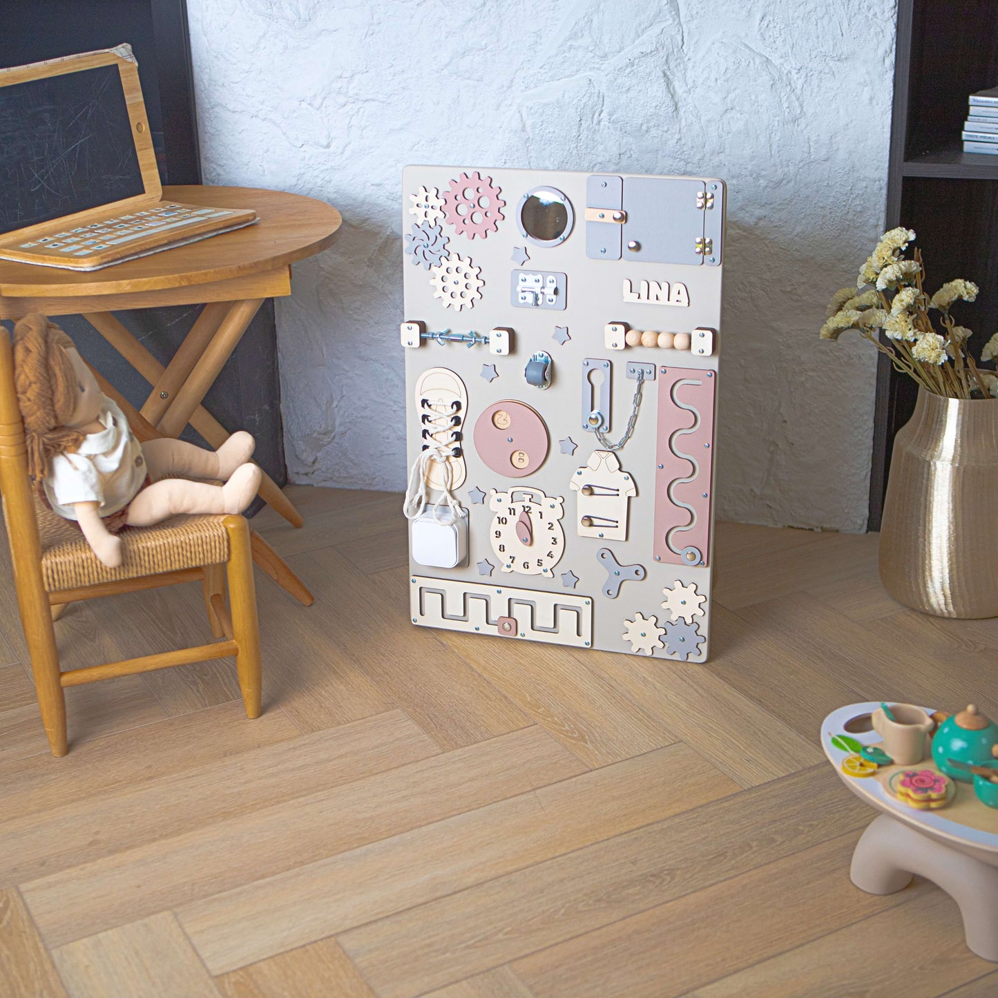 Aktivitätsbrett für Kinder mit verschiedenen pädagogischen Elementen auf einem Holzboden.