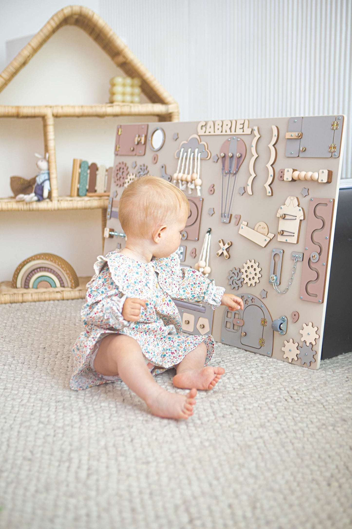 Bébé jouant avec un busy board en bois dans une chambre d'enfant