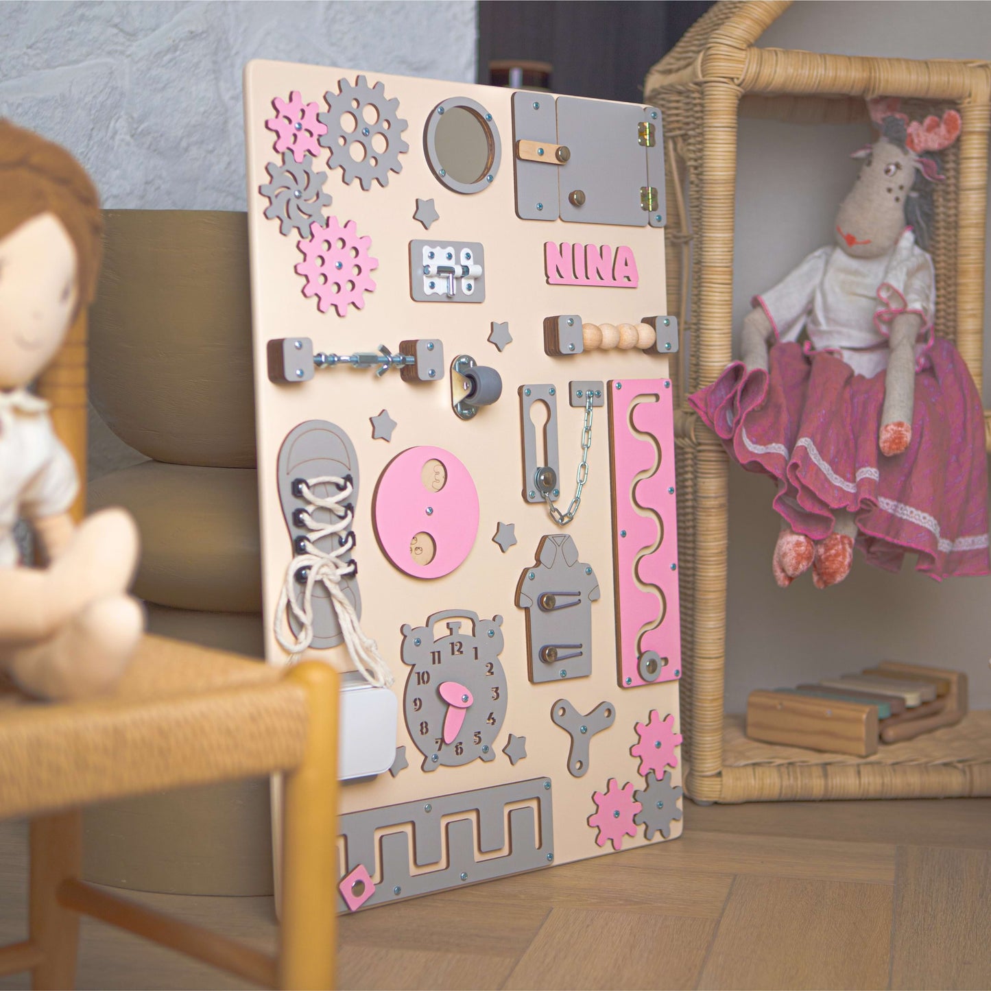 Children's educational board with various shapes and letters, featuring the name 'Nina', in a room setting.