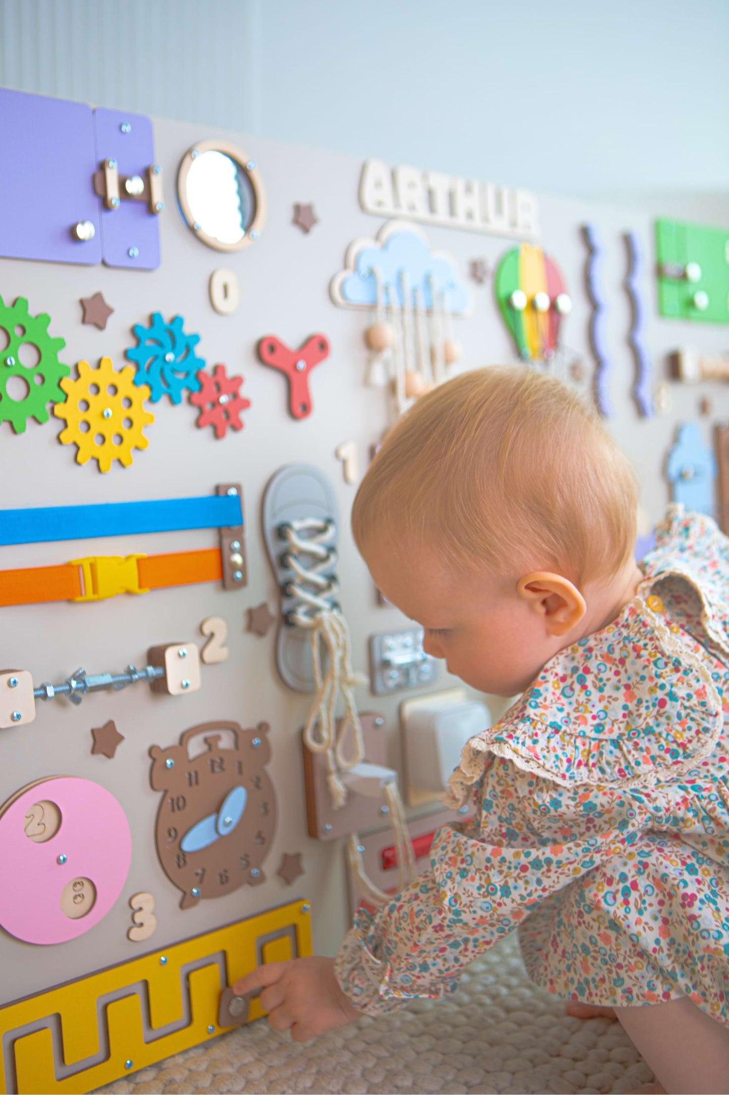 Enfant interagissant avec un panneau mural éducatif coloré.