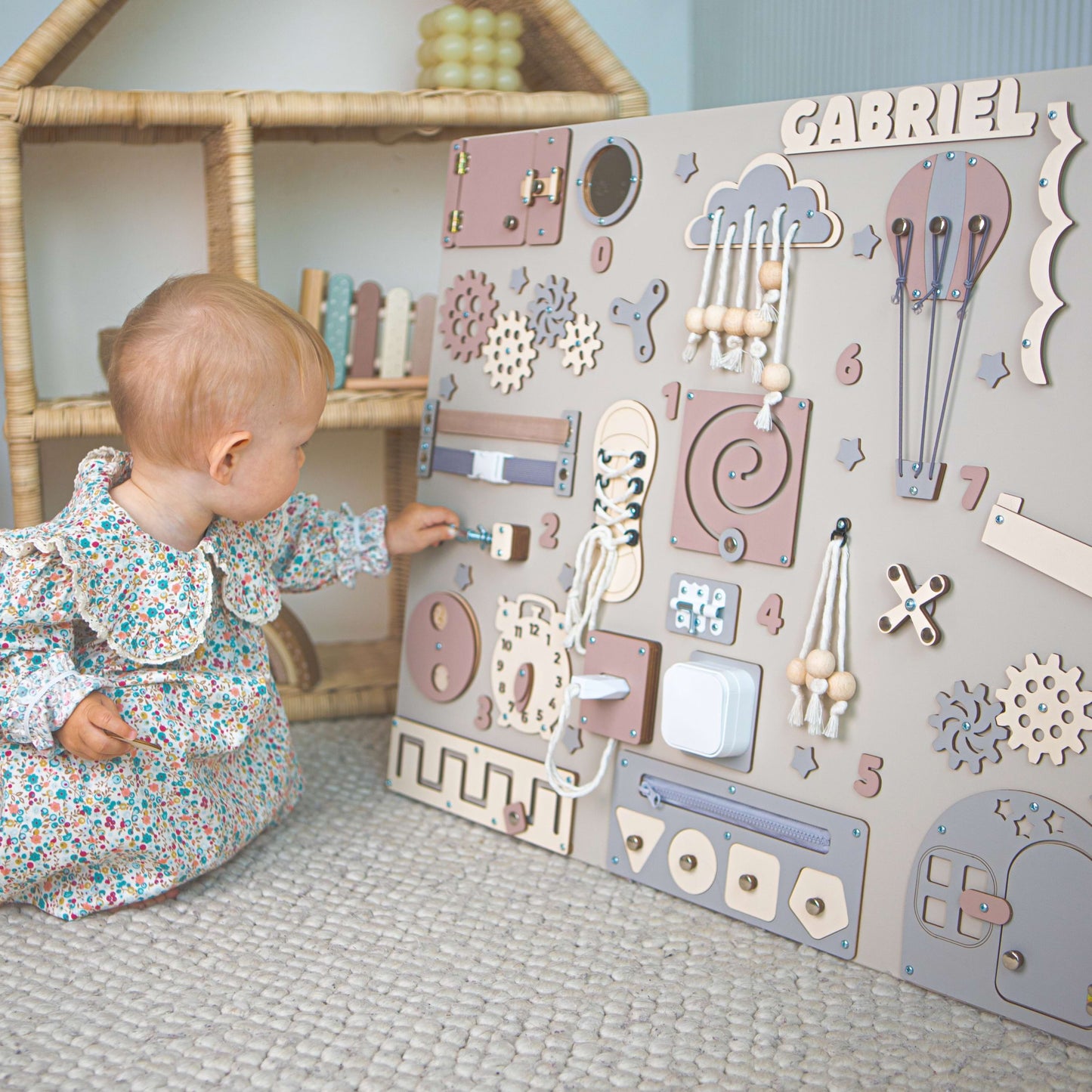 Enfant jouant avec un tableau d'activités en bois comportant divers éléments éducatifs.