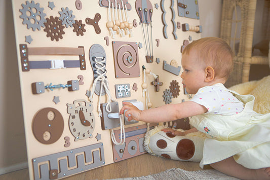 Bébé jouant avec un panneau d'activités en bois dans un cadre familial