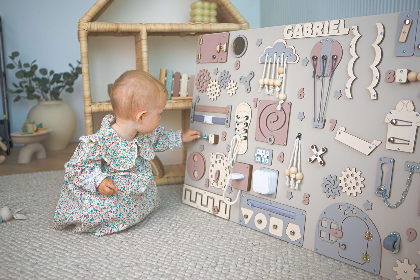 Baby playing with a wooden activity board in a child's playroom.