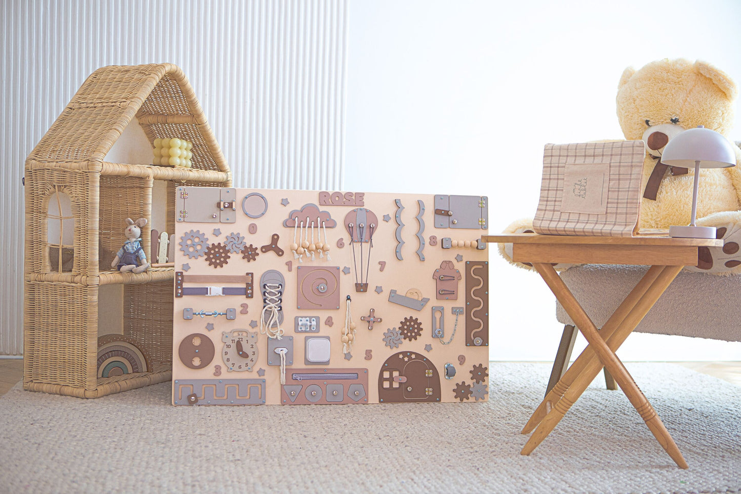 Baby playing with a wooden activity board in a room with a wicker basket and dollhouse.