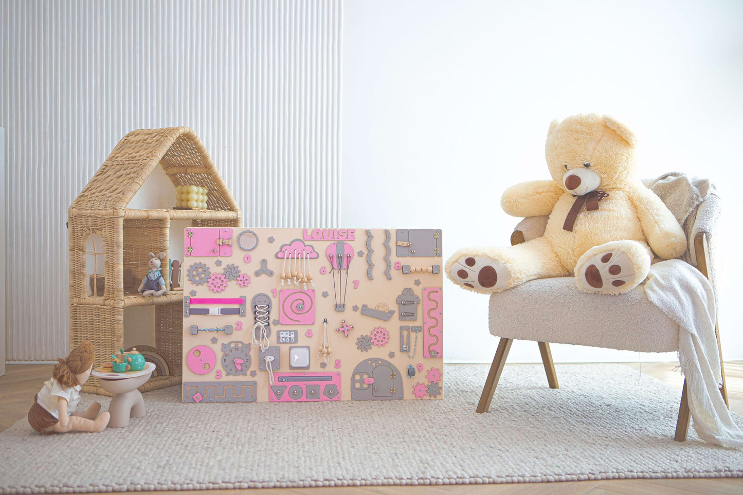 Children's play area with a large activity board, toy box, and teddy bear on a chair.