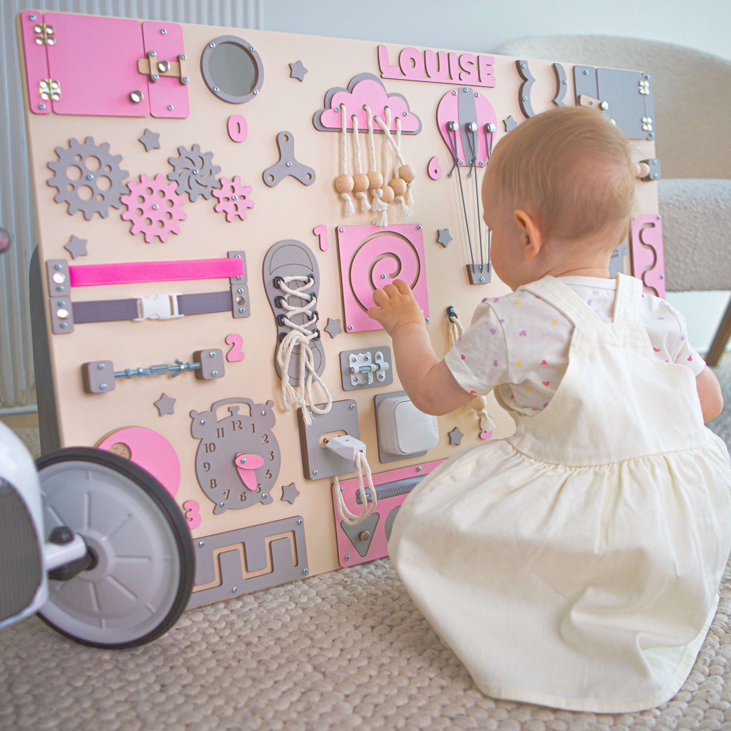 Baby spielt mit einem pädagogischen Spielbrett mit verschiedenen interaktiven Elementen.