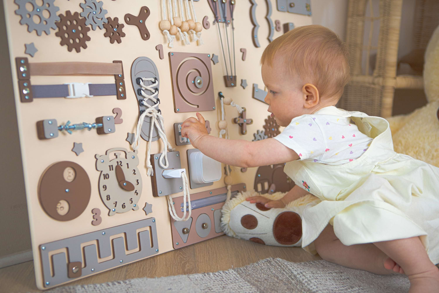 Baby spielt mit einem motorikbrett mit verschiedenen Formen und Strukturen.