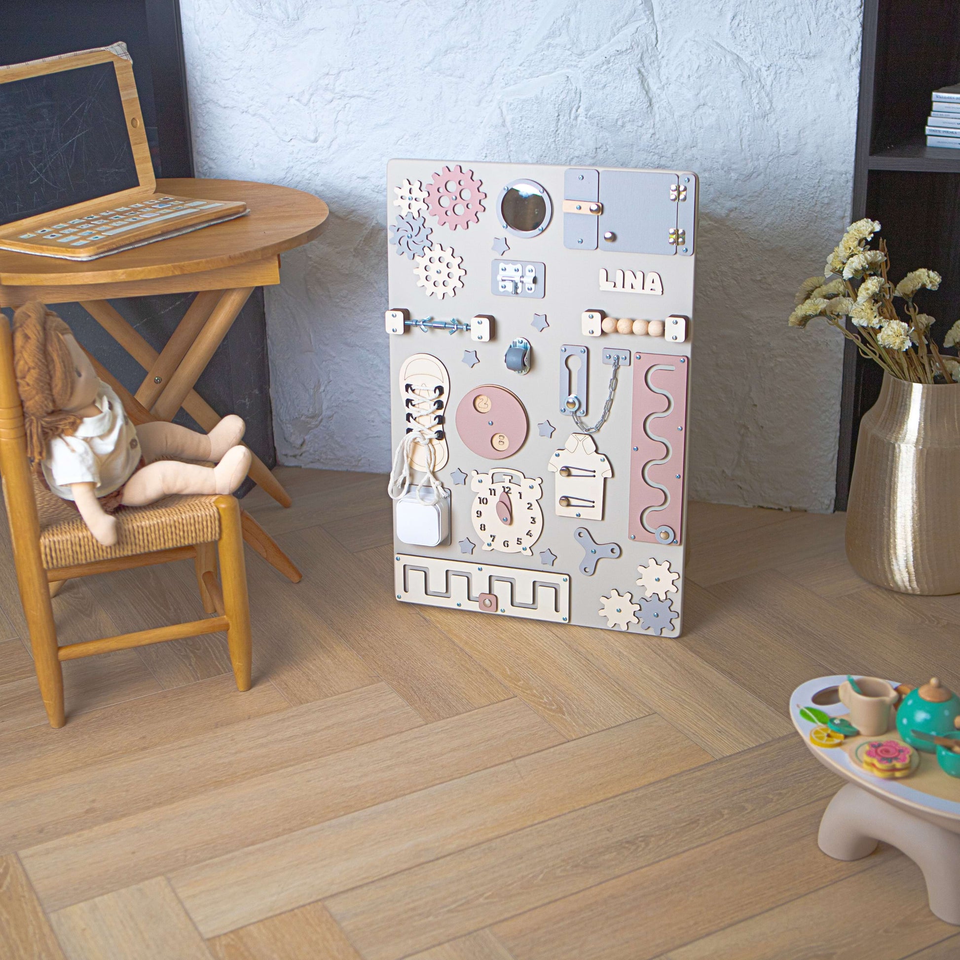 Aktivitätsbrett für Kinder mit verschiedenen pädagogischen Elementen auf einem Holzboden.