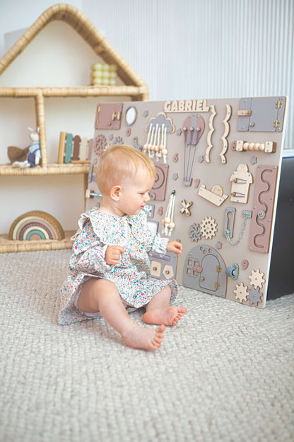 Bébé jouant avec un tableau d'activités en bois dans une chambre d'enfant