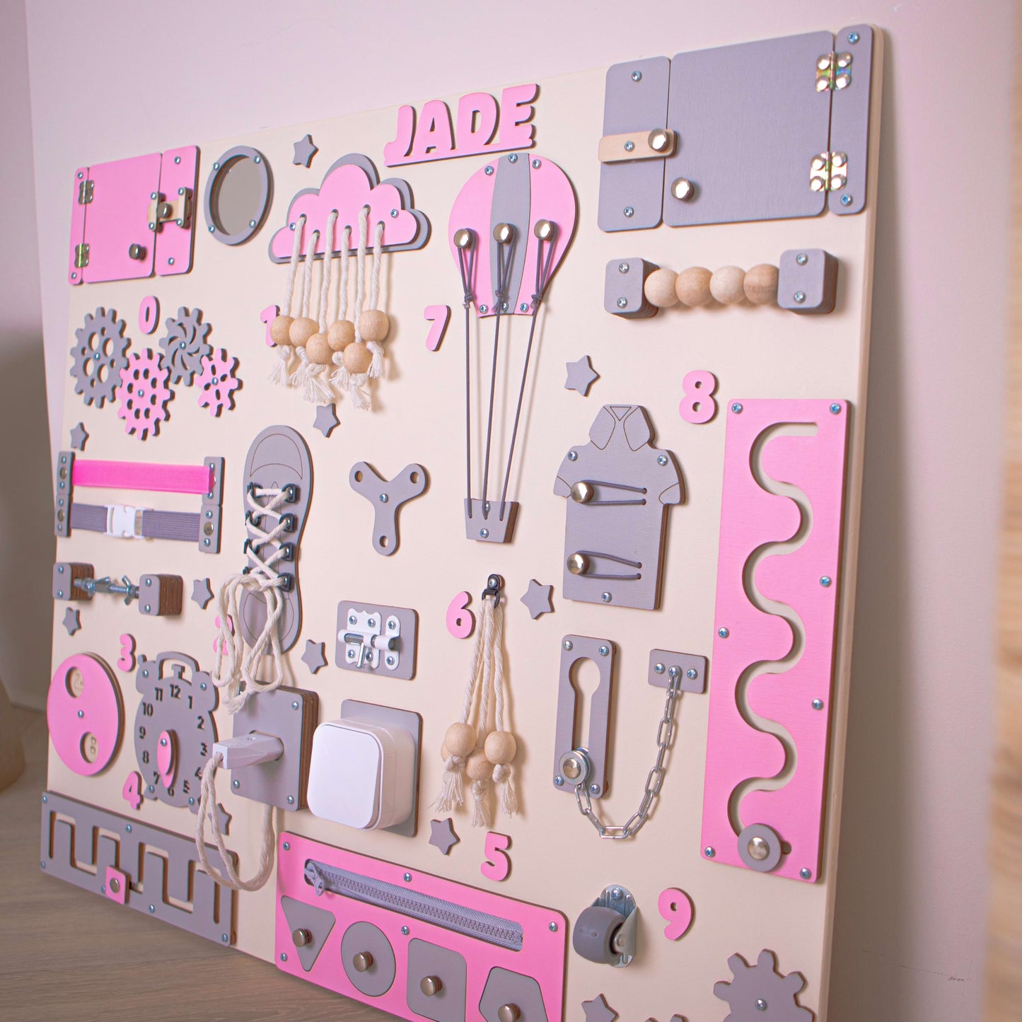 Tableau d'activités rose pour enfants avec divers outils éducatifs sur fond beige