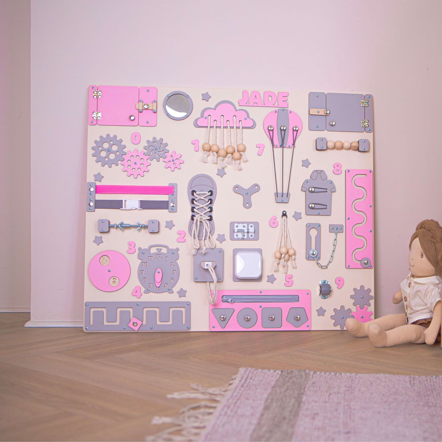 Table Montessori rose pour enfants avec divers éléments éducatifs sur un sol en bois.