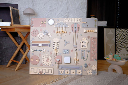 Tableau Montessori pastel pour enfants avec différentes formes et motifs sur un sol en bois.